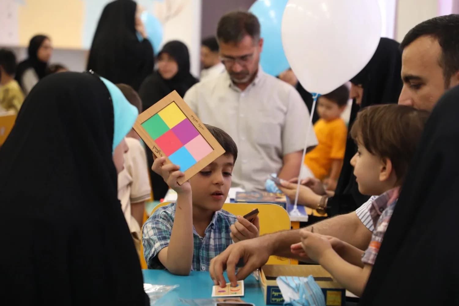 پسربچه‌ای نقاشی رنگی‌اش را بالا گرفته است