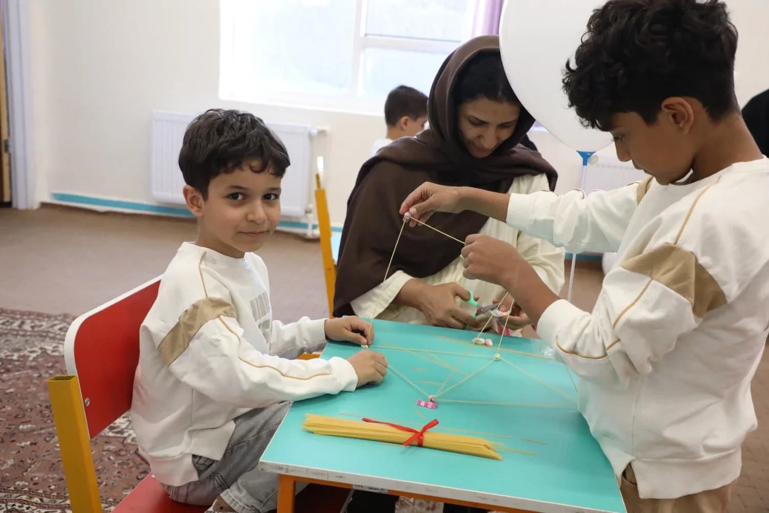 دو پسربچه در حال ساخت سازه با ماکارونی